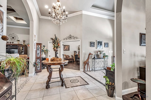 foyer entrance featuring baseboards, a tray ceiling, ornamental molding, light tile patterned floors, and a notable chandelier