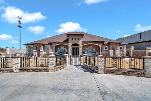 mediterranean / spanish-style home with stone siding, stucco siding, a shingled roof, and fence