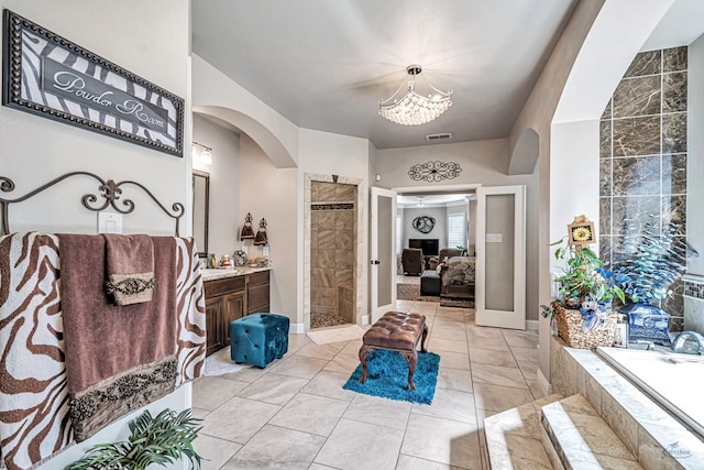 bathroom featuring tiled shower, ensuite bathroom, an inviting chandelier, a bath, and vanity