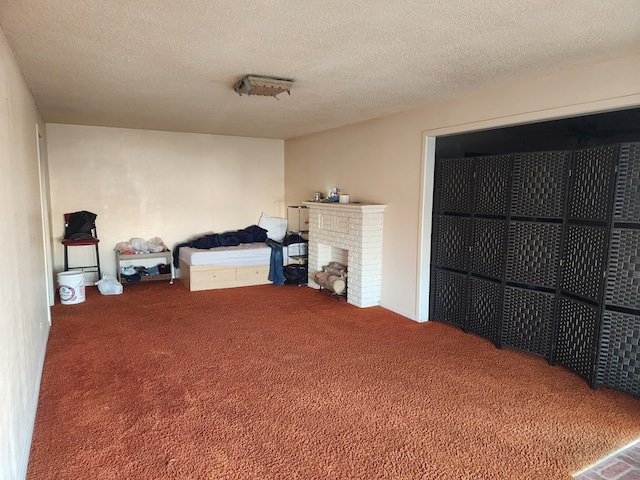 carpeted bedroom with a textured ceiling and a brick fireplace