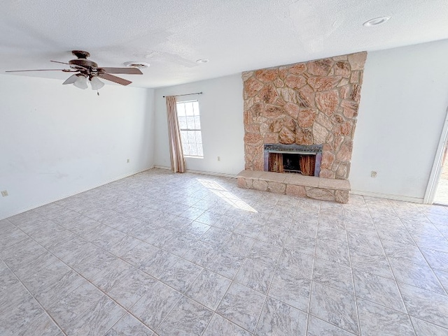 unfurnished living room featuring a ceiling fan, a stone fireplace, and a textured ceiling