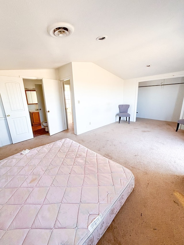 unfurnished bedroom featuring lofted ceiling, visible vents, and light colored carpet