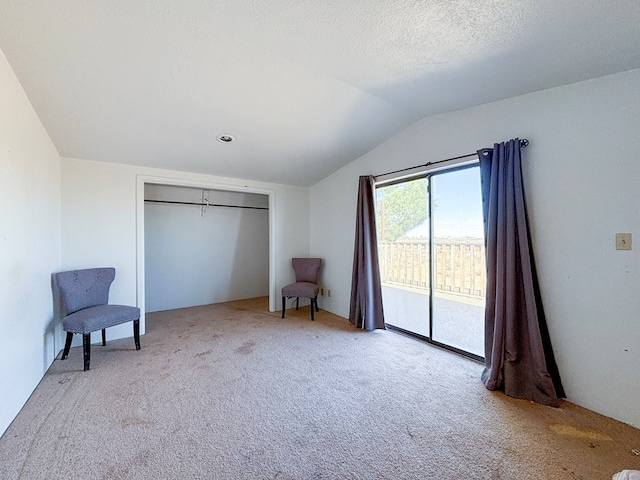 unfurnished room featuring lofted ceiling, a textured ceiling, and carpet flooring