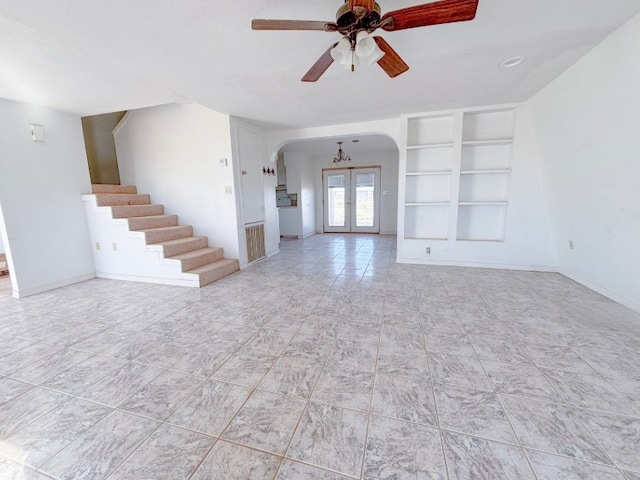 unfurnished living room featuring baseboards, arched walkways, stairway, french doors, and built in shelves