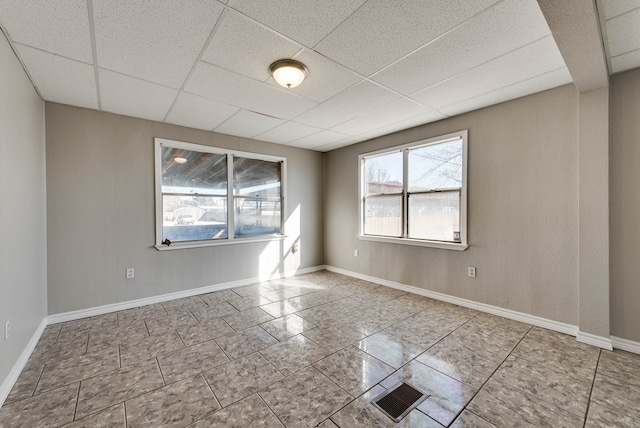 spare room with light tile patterned floors and a paneled ceiling