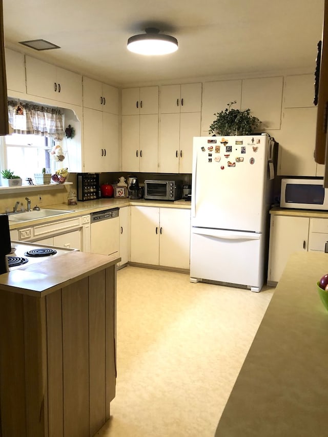 kitchen featuring white cabinets, white appliances, and sink