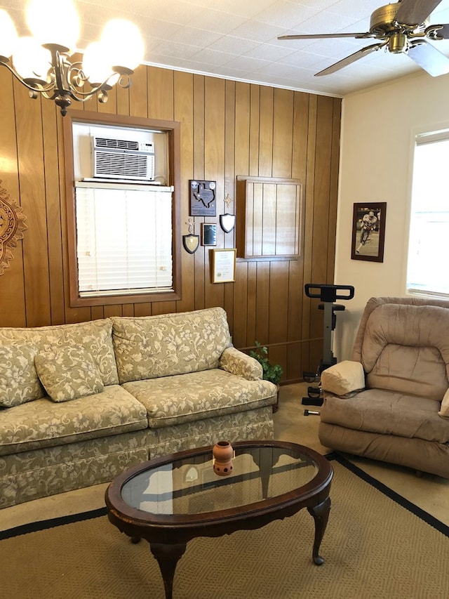 carpeted living room featuring ceiling fan with notable chandelier, an AC wall unit, and wooden walls