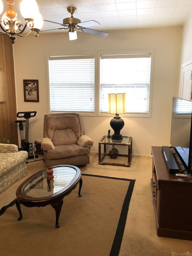 carpeted living room featuring ceiling fan with notable chandelier