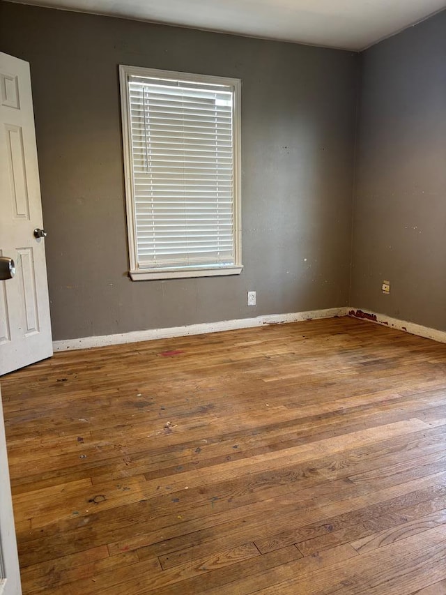 spare room with baseboards and wood finished floors