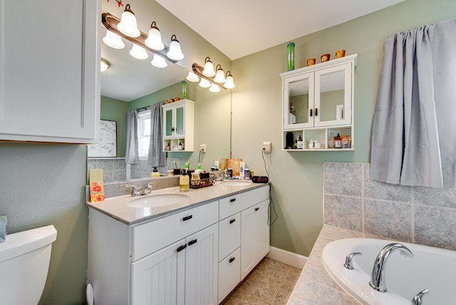 bathroom with tile patterned flooring, vanity, a relaxing tiled tub, and toilet