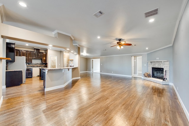 unfurnished living room with light hardwood / wood-style floors, ceiling fan, and crown molding