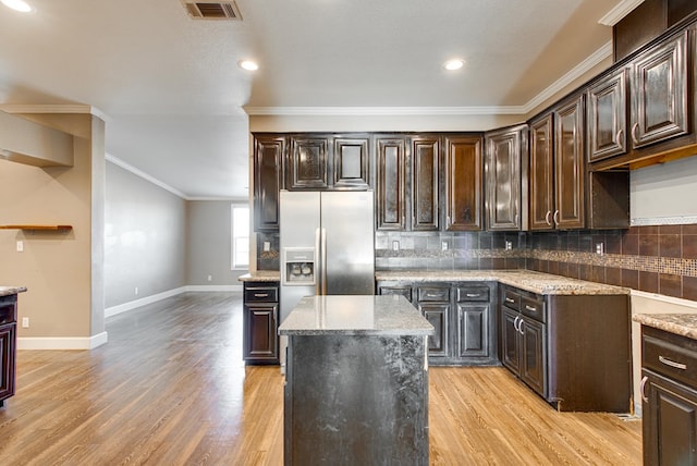 kitchen with stainless steel refrigerator with ice dispenser, dark brown cabinetry, and a kitchen island