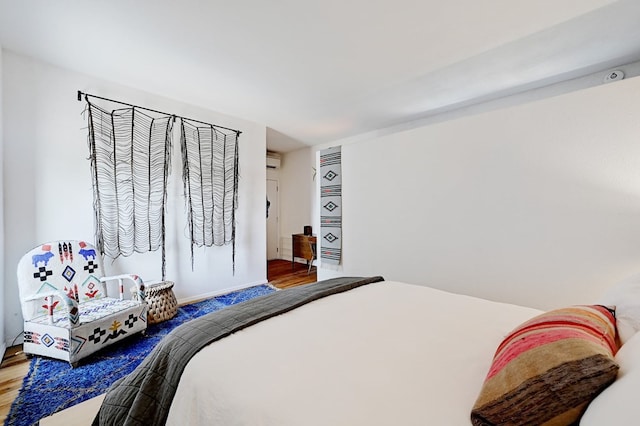 bedroom with a wall mounted air conditioner and wood finished floors