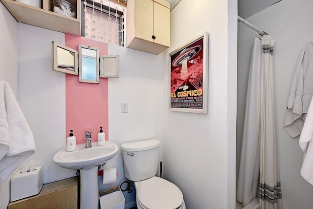 bathroom featuring a shower with shower curtain, a sink, and toilet