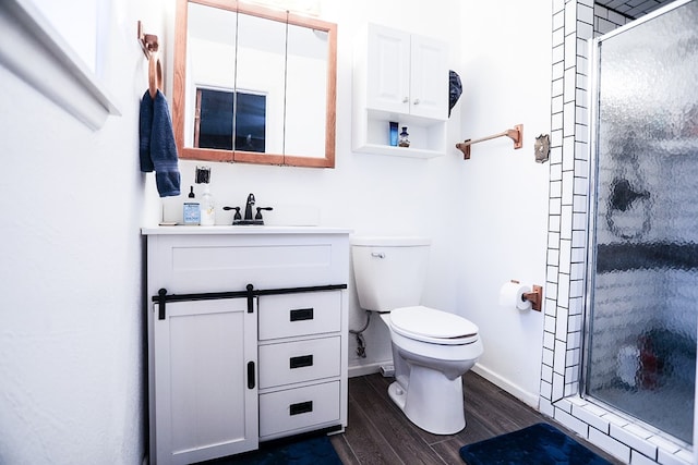 full bath featuring vanity, wood finished floors, baseboards, a stall shower, and toilet