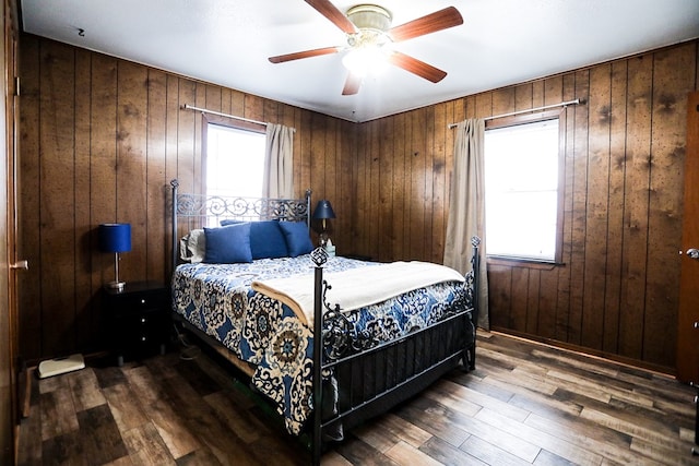 bedroom with ceiling fan, wood finished floors, and wood walls