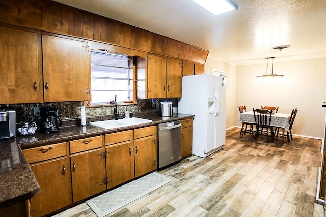 kitchen featuring visible vents, a sink, white refrigerator with ice dispenser, light wood finished floors, and dishwasher