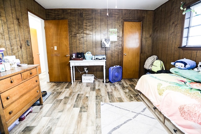 bedroom featuring light wood-type flooring and wood walls