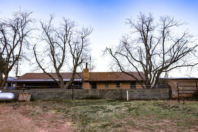 back of property with a chimney and fence