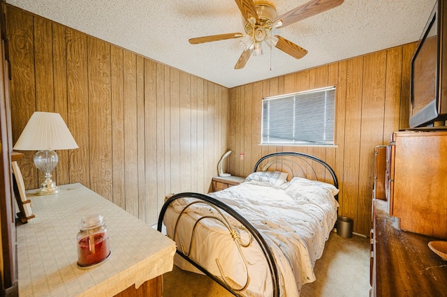 bedroom with ceiling fan, a textured ceiling, wood walls, and carpet flooring