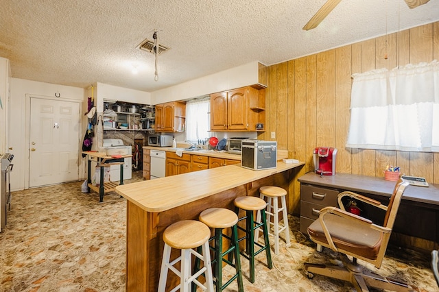 kitchen with stainless steel microwave, visible vents, wooden walls, white dishwasher, and open shelves