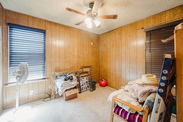 carpeted bedroom featuring a textured ceiling, ceiling fan, and wooden walls