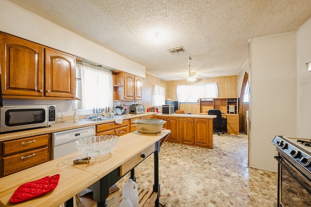 kitchen with visible vents, stainless steel microwave, gas stove, a peninsula, and white dishwasher