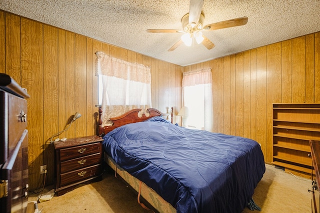 bedroom with wood walls, a textured ceiling, ceiling fan, and carpet floors