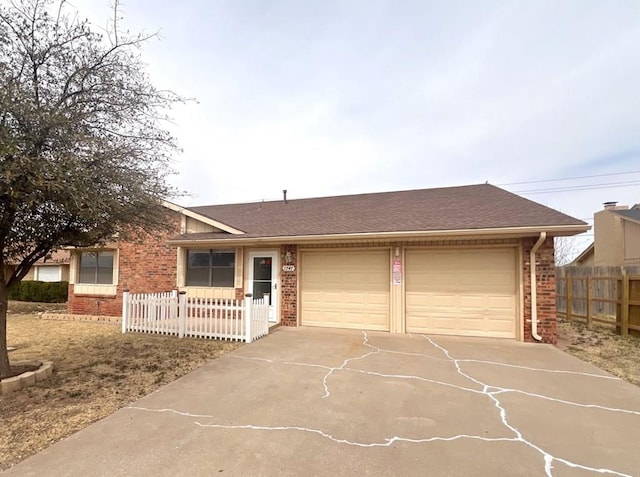 ranch-style house featuring a garage, brick siding, driveway, and fence