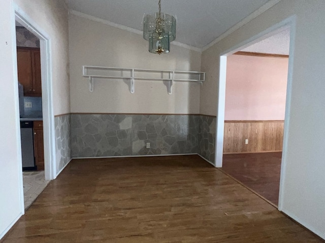 unfurnished dining area featuring ornamental molding, wood finished floors, a wainscoted wall, and a chandelier