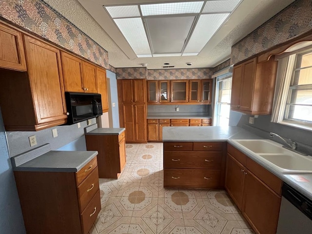 kitchen featuring a healthy amount of sunlight, brown cabinetry, a sink, black microwave, and dishwasher