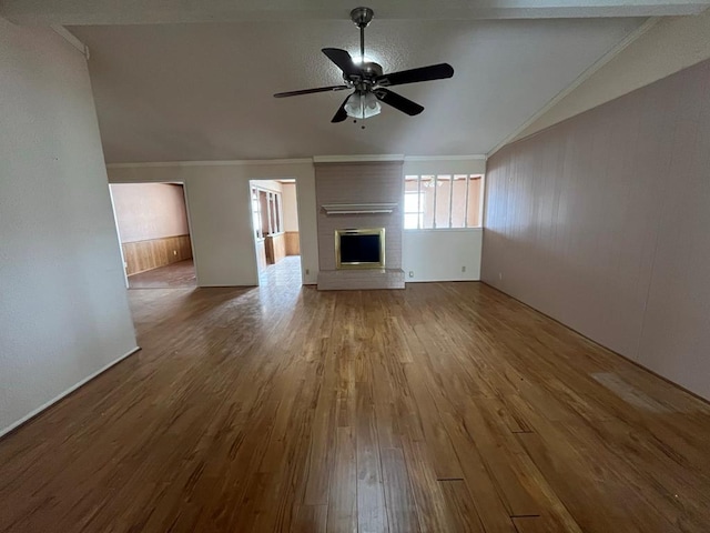 unfurnished living room with a ceiling fan, a brick fireplace, wood finished floors, and crown molding