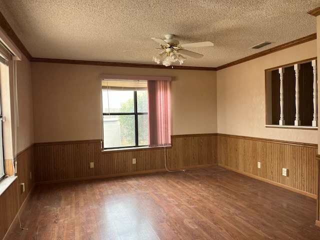 spare room with wainscoting, a textured ceiling, and wood finished floors