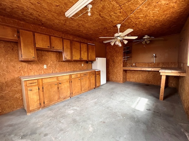 kitchen with light countertops, unfinished concrete flooring, and brown cabinetry