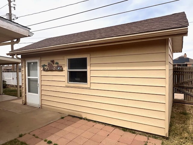 view of home's exterior featuring a patio area, fence, and a shingled roof