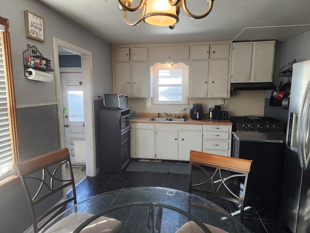 kitchen with stainless steel fridge, sink, white cabinets, and an inviting chandelier