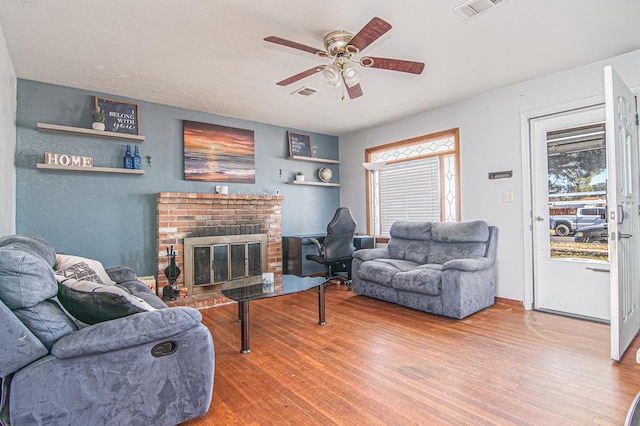 living room featuring ceiling fan, a fireplace, and wood-type flooring