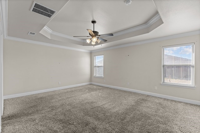 empty room featuring carpet, ceiling fan, ornamental molding, and a tray ceiling