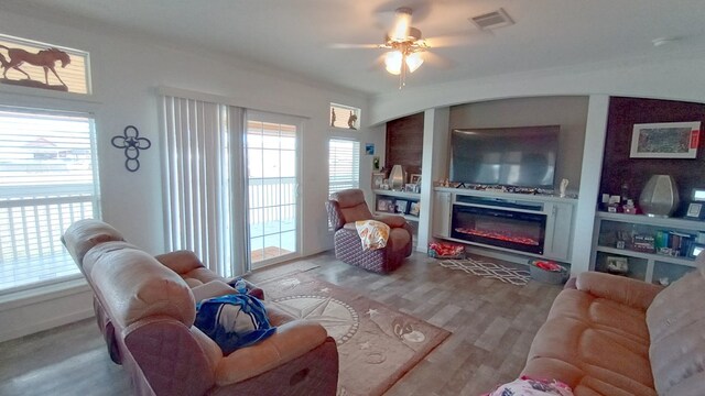 living room with ceiling fan, plenty of natural light, and light hardwood / wood-style floors