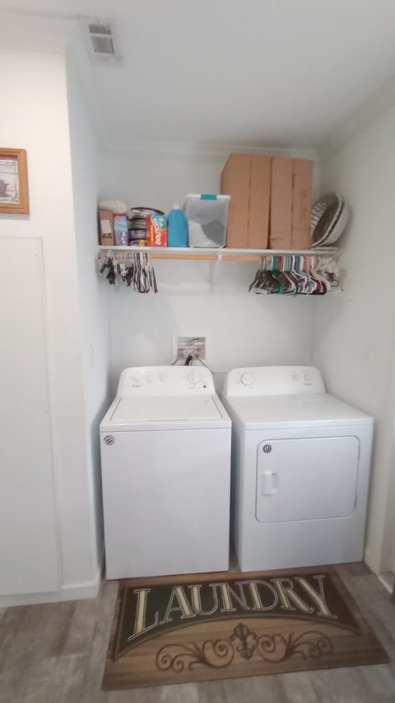 washroom with washing machine and clothes dryer, crown molding, and hardwood / wood-style floors