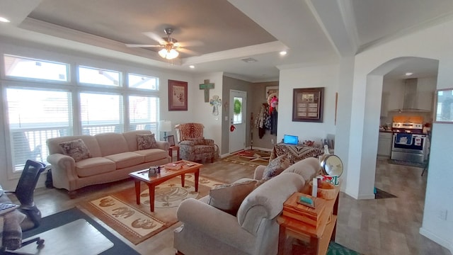 living room featuring ceiling fan, a raised ceiling, wood-type flooring, and crown molding