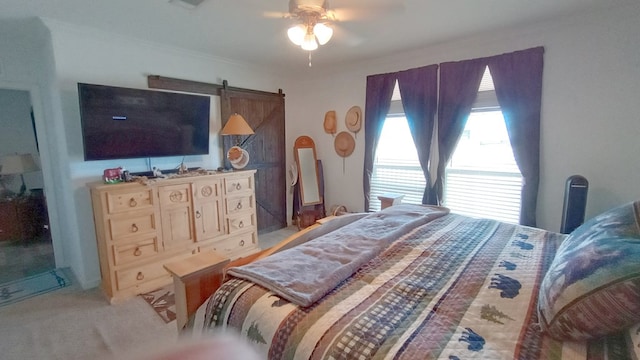 carpeted bedroom featuring a barn door and ceiling fan