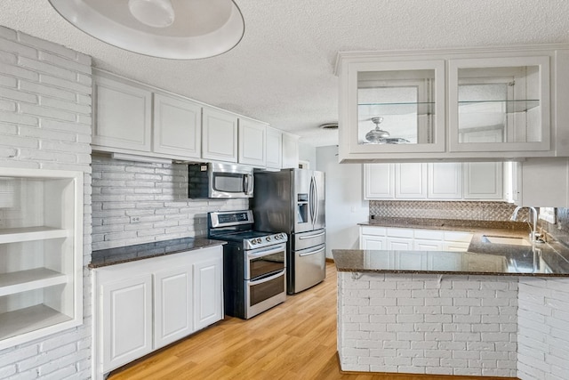 kitchen featuring sink, light hardwood / wood-style flooring, appliances with stainless steel finishes, white cabinetry, and kitchen peninsula