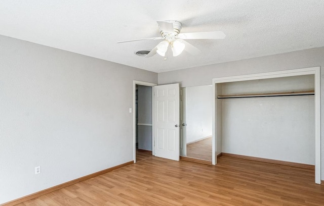 unfurnished bedroom featuring ceiling fan, a closet, a textured ceiling, and light wood-type flooring