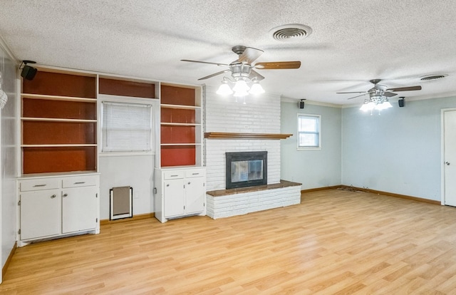 unfurnished living room featuring ceiling fan, light hardwood / wood-style flooring, a textured ceiling, and a brick fireplace