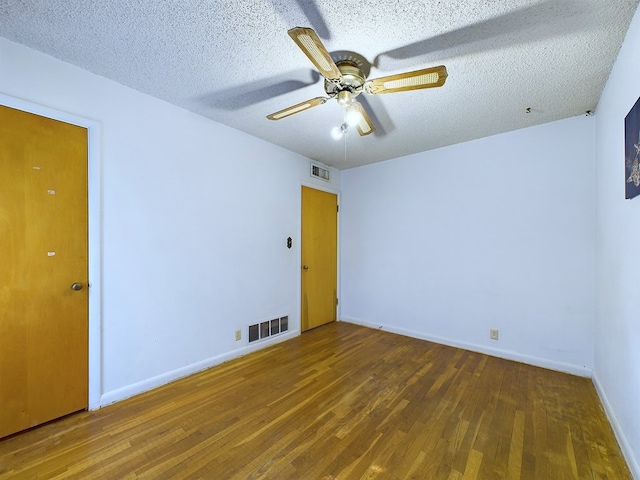 spare room featuring a textured ceiling, dark wood-type flooring, and ceiling fan