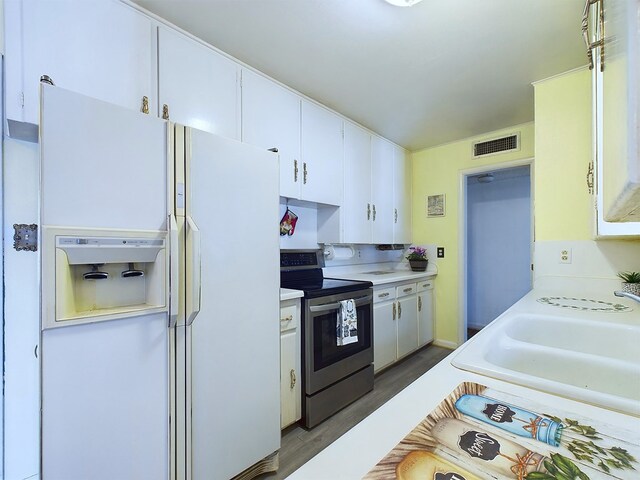 kitchen with white cabinets, stainless steel range with electric cooktop, wood-type flooring, white refrigerator with ice dispenser, and sink