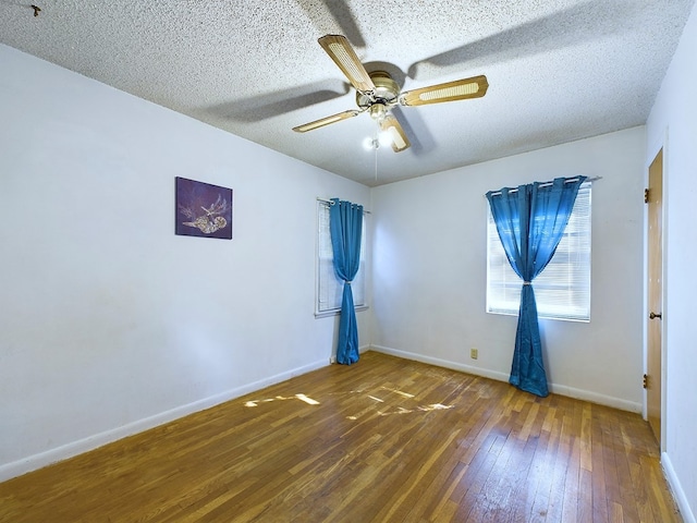 empty room with ceiling fan, a textured ceiling, and dark hardwood / wood-style flooring