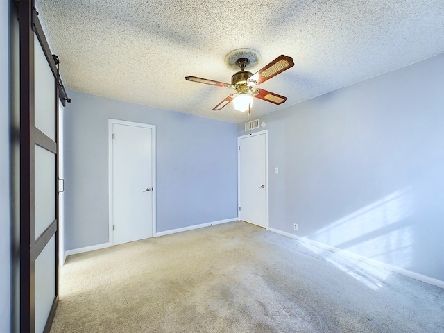 spare room featuring ceiling fan, light colored carpet, and a textured ceiling