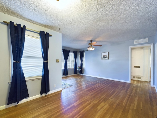 spare room with a textured ceiling, ceiling fan, and dark hardwood / wood-style flooring